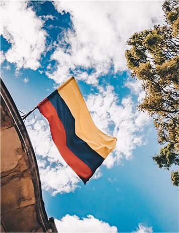 Colombian flag waving outdoors against a bright blue sky, representing LionTrust's connection with Colombia.