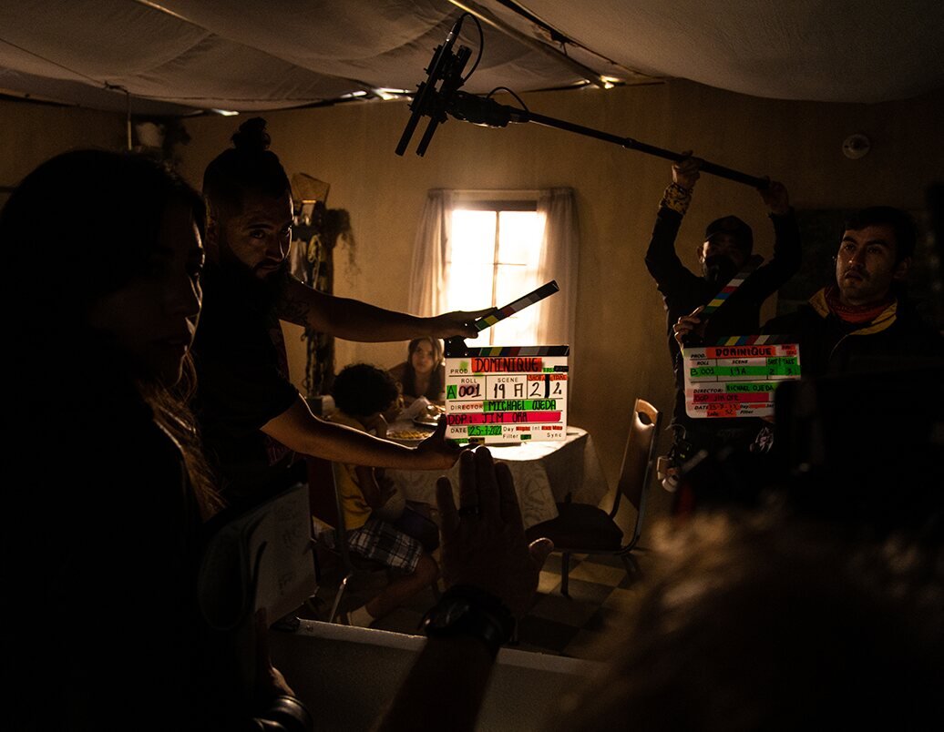 Film crew working around a clapperboard and lighting equipment on an interior production set.